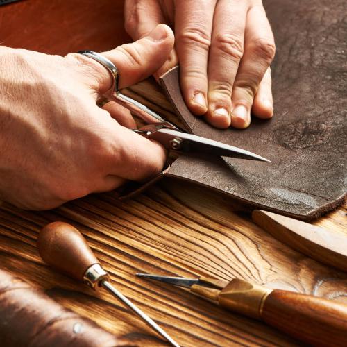 Cutting the piece of leather with a hand scissors.